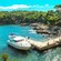 Un bote para cruceros atracado en una caleta verde con una pequeña casa